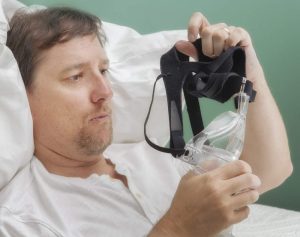 Image of a man holding and examining his CPAP mask