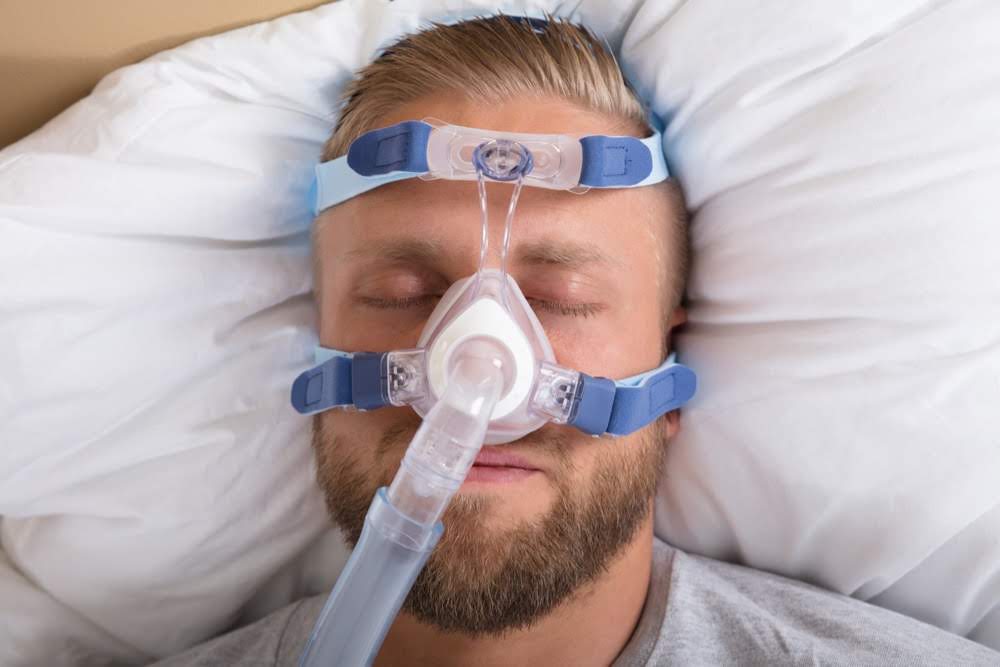Sleeping man with nasal CPAP machine