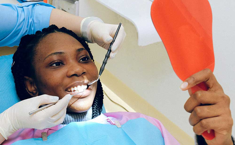 Patient holding mirror and observing the sensitive teeth treatment